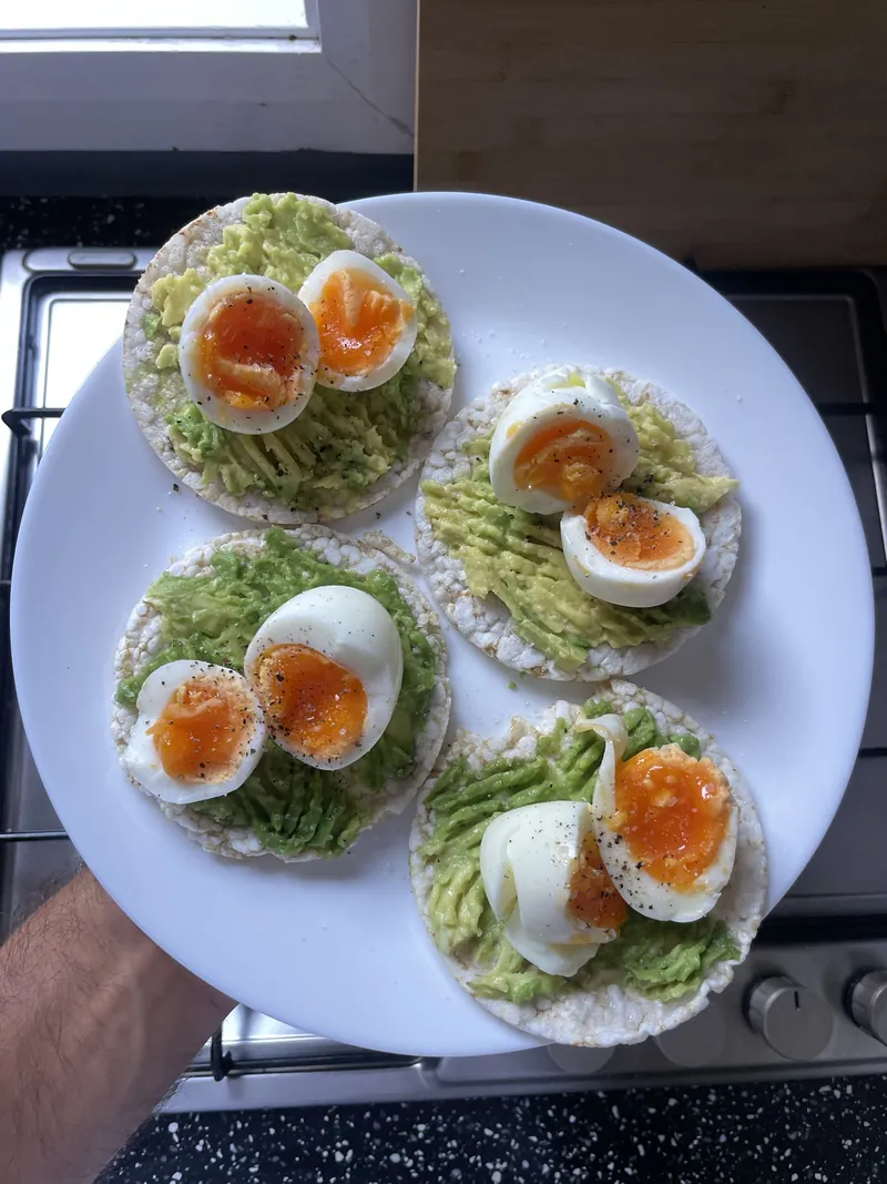Four rice cakes topped with smashed avocado and halved jammy boiled eggs